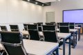 Training room with rows of desks, chairs and a wall-mounted display