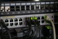 Access switch below a numbered patch panel with live port activity lights
