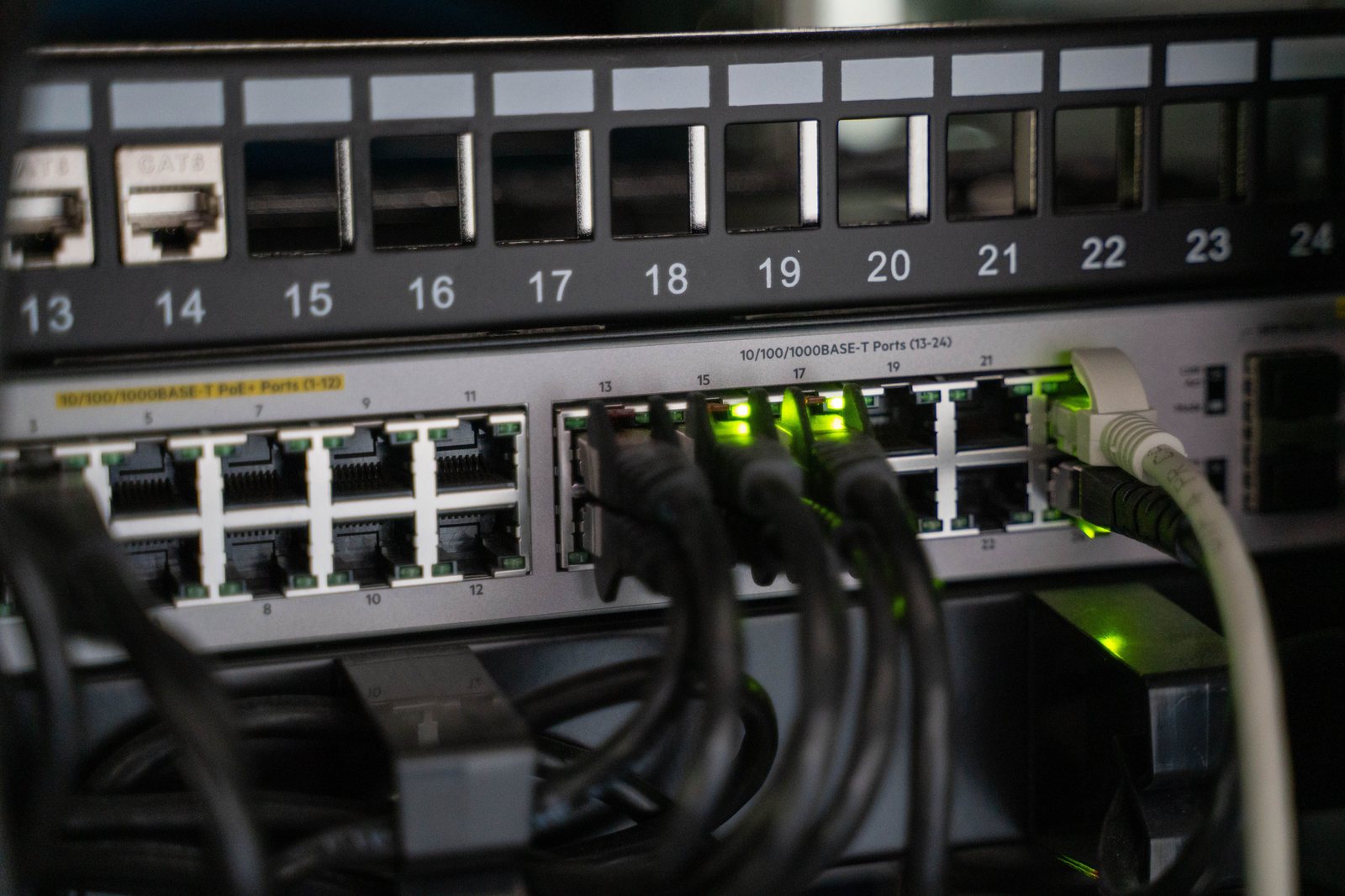 Access switch below a numbered patch panel with live port activity lights