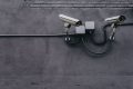 Two bullet surveillance cameras on a concrete wall with conduit-routed cabling
