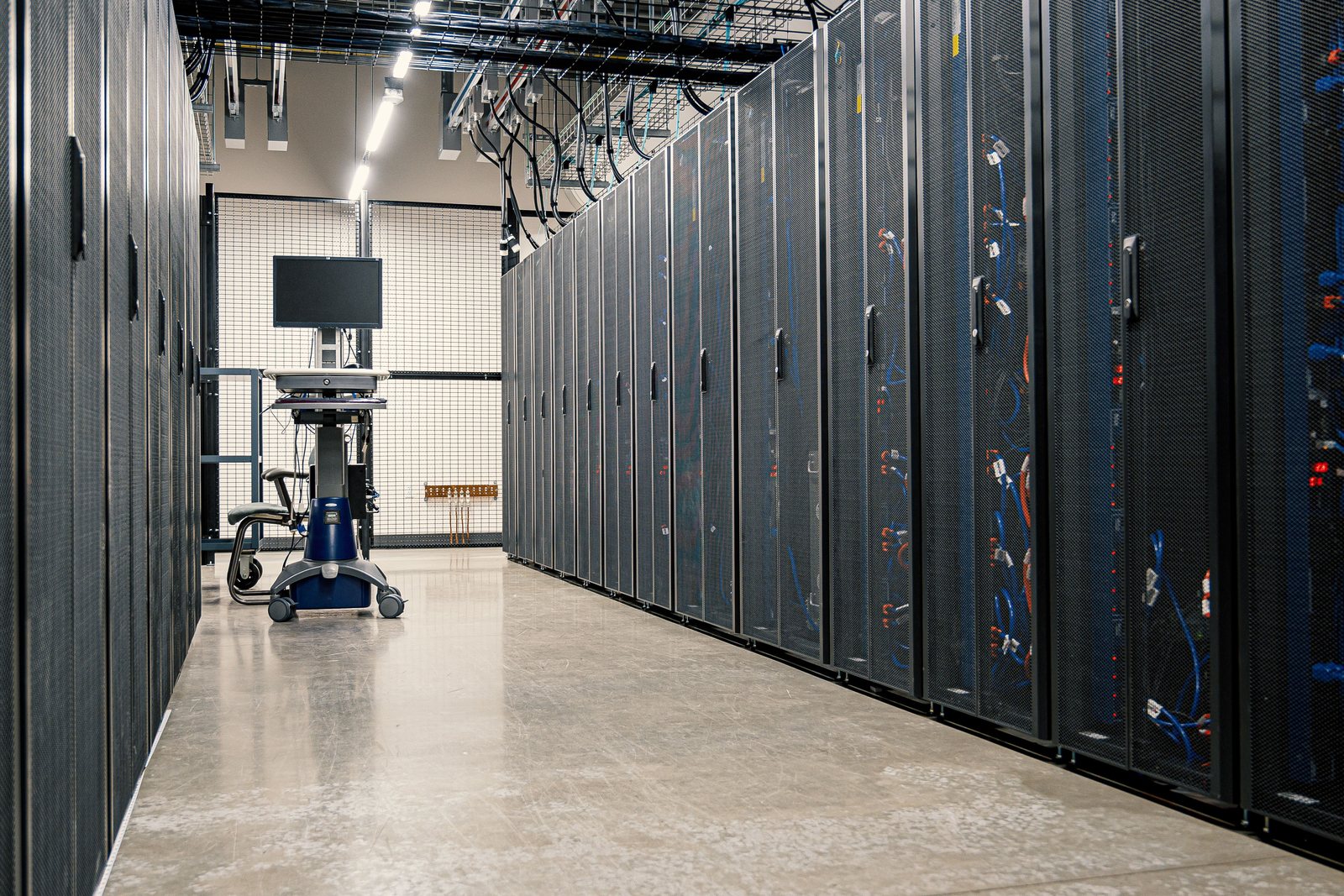 Server room aisle with closed racks and a crash-cart workstation