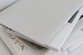 Closed laptop on a stack of documents, representing endpoint asset records