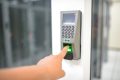 Door access reader with keypad and fingerprint sensor beside an office entrance