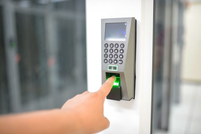 Door access reader with keypad and fingerprint sensor beside an office entrance