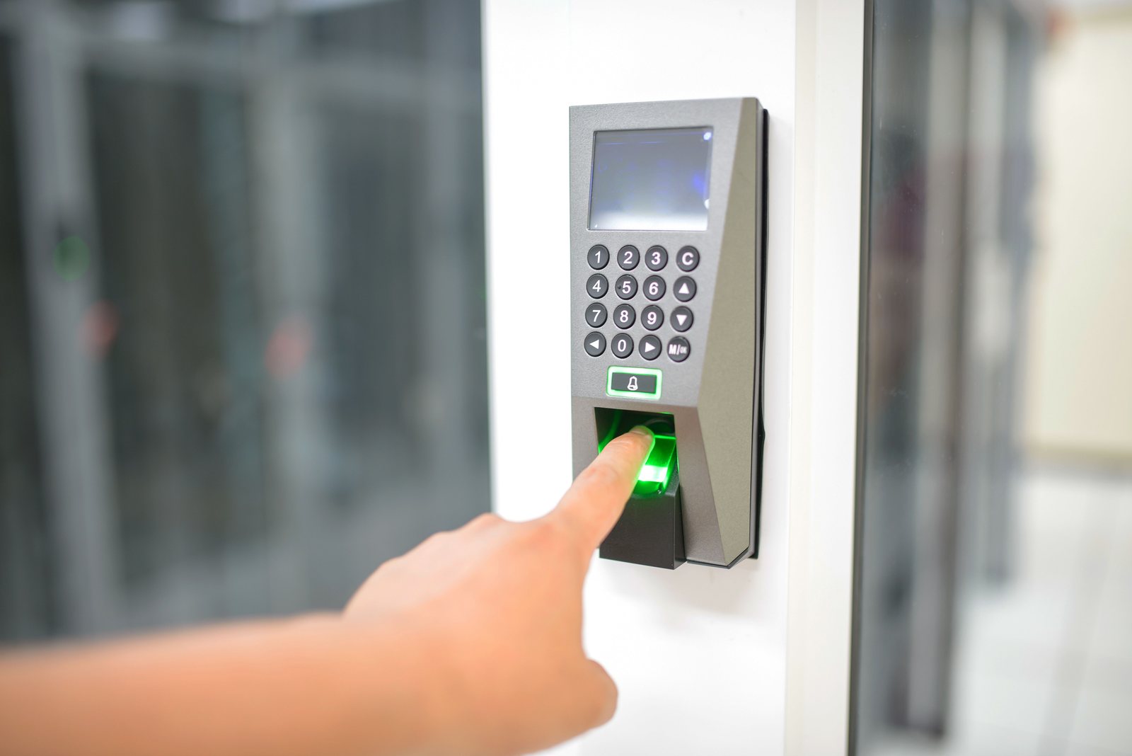 Door access reader with keypad and fingerprint sensor beside an office entrance