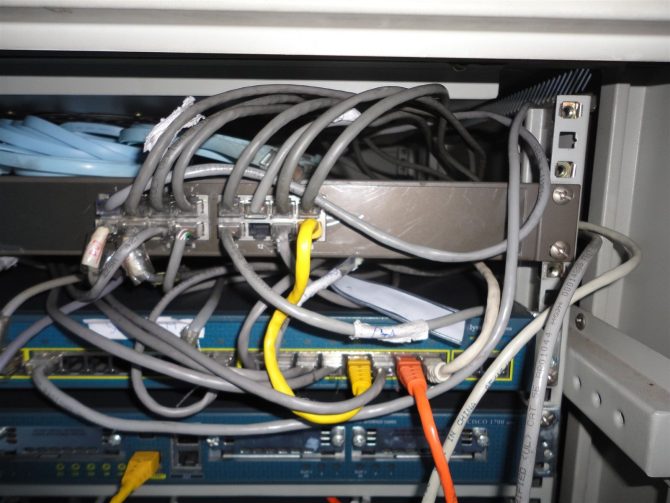 Rack before tidy-up: unmanaged patch cords looping over a patch panel and switches, the condition a hygiene pass corrects